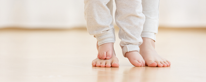 Barneføtter tråkker på voksenføtter.