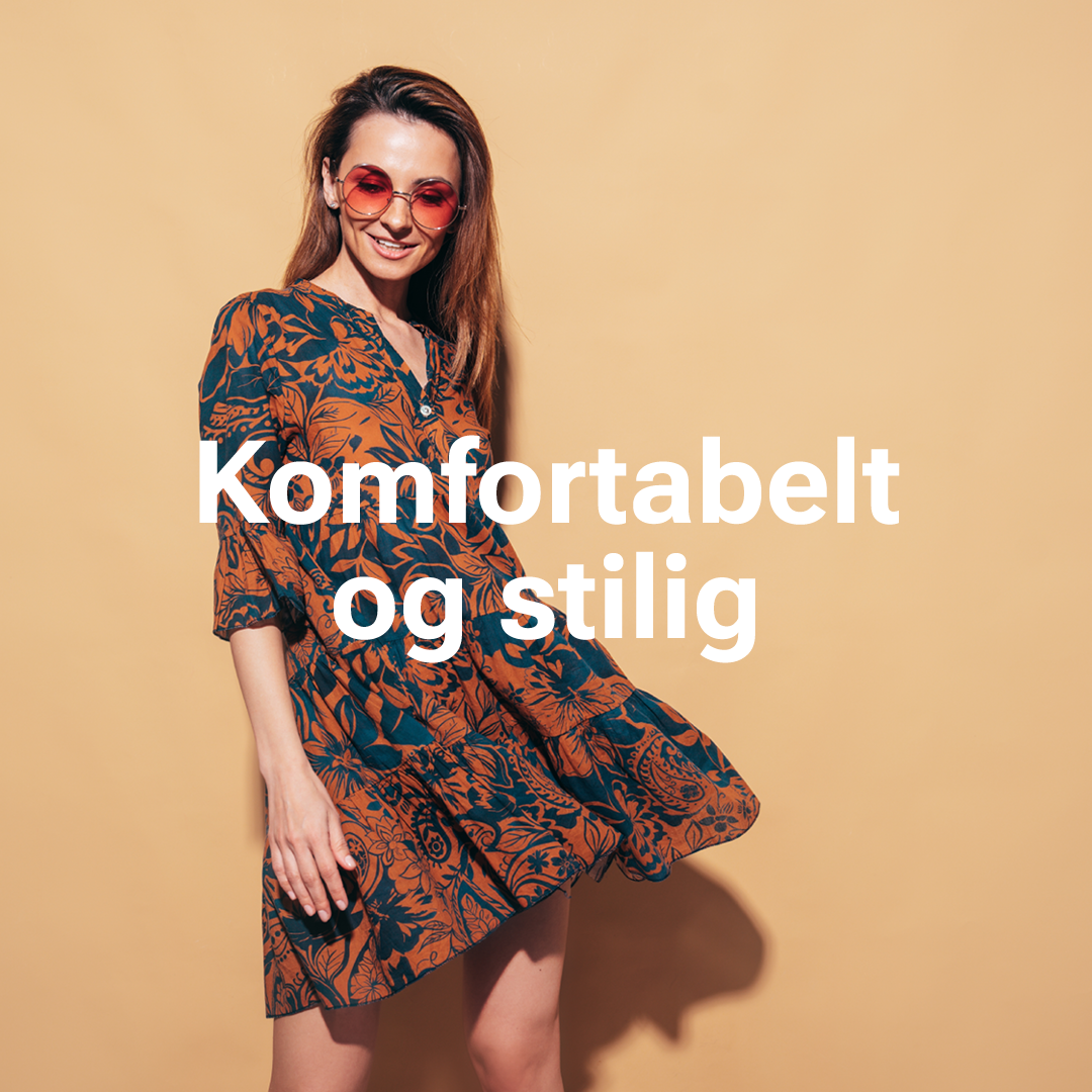 Person i blomstret oransje og blå kjole med rosa solbriller mot beige bakgrunn. Tekst: "Komfortabelt og stilig".
